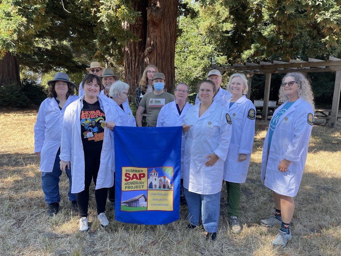 group in lab coats holding banner at avocado tree